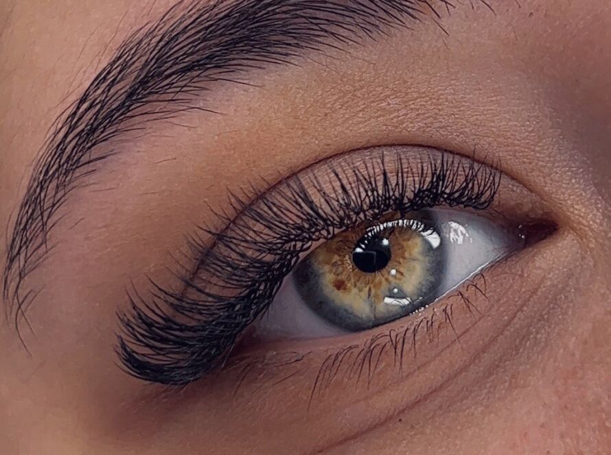 Close-up of a bride's eye with voluminous lash extensions and a warm hazel iris, showcasing flawless wedding-day beauty.