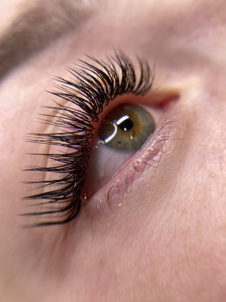 Extreme close-up of green-hazel eye with spiky volume lash extensions showing dramatic separation and textured fan pattern
