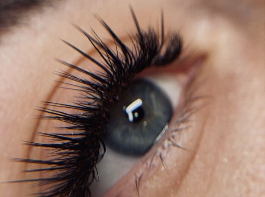 Close-up of blue-gray eye with dramatic spiky volume lash extensions showing extreme separation and textured definition