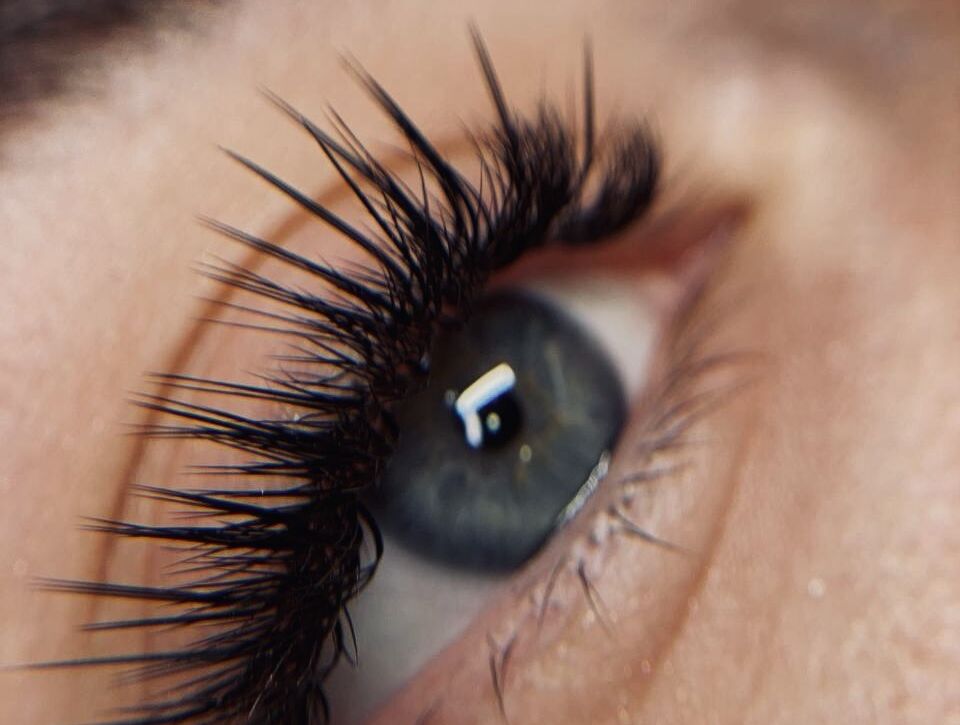 Close-up of blue-gray eye with dramatic spiky volume lash extensions showing extreme separation and textured definition