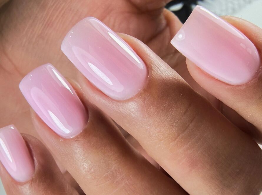Close-up of glossy soft pink square nails with a clean finish and smooth cuticle line.