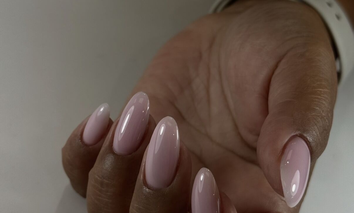 Soft pink gel manicure on oval nails with high-gloss finish on dark skin tone