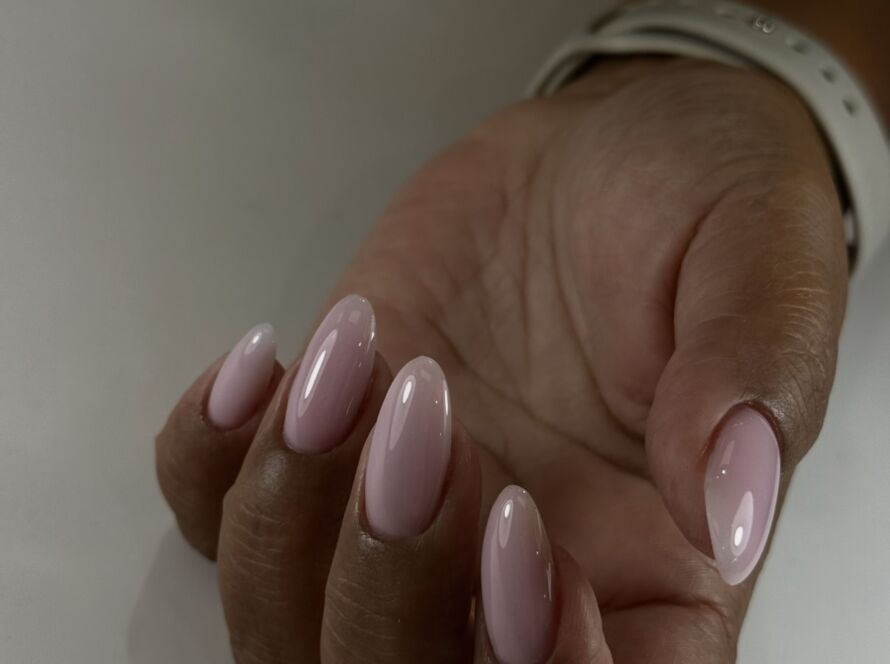 Soft pink gel manicure on oval nails with high-gloss finish on dark skin tone